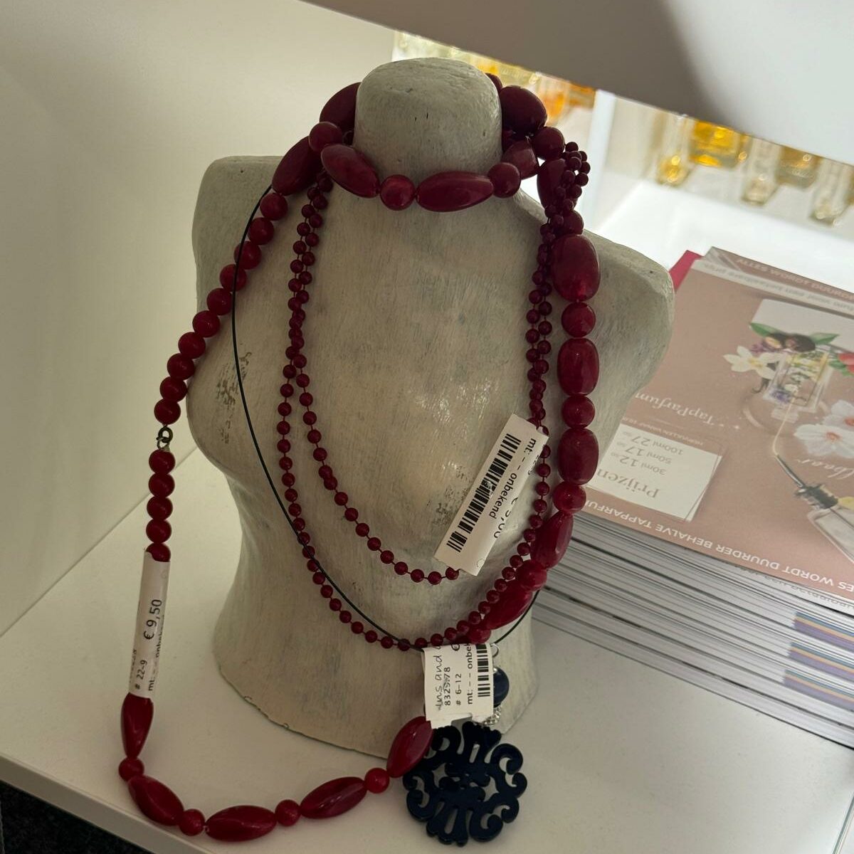 A mannequin with red-beaded necklaces. 